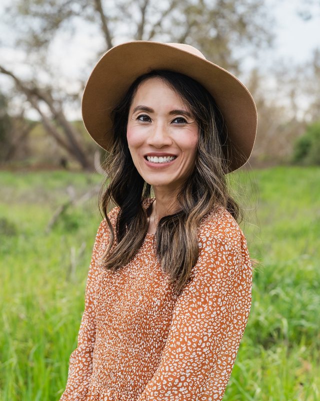 Sharon Go in a sun hat, smiling in a green field
